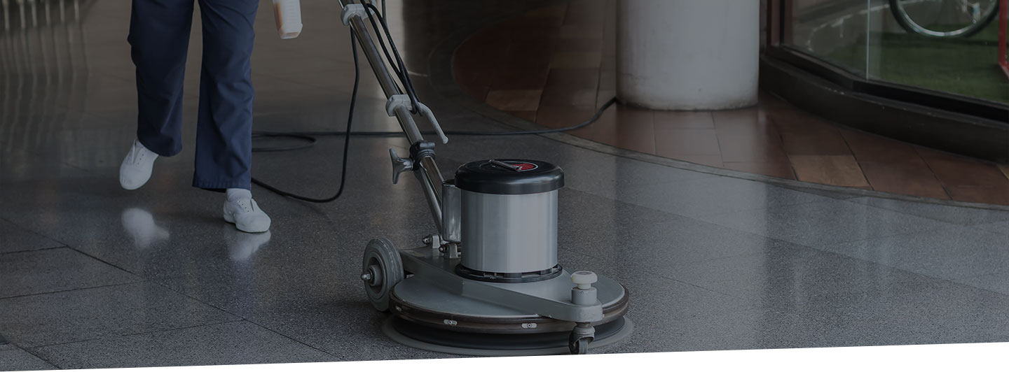 Cropped image of commercial floor cleaner being operated by professional cleaner.